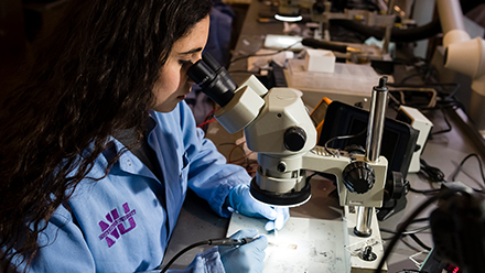 Student viewing biomedical device through a microscope