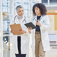 Two medical professionals walking with clipboards