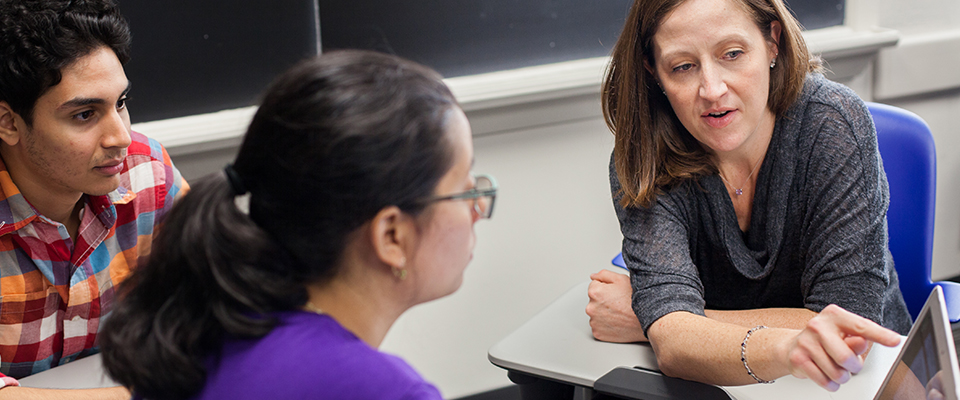 Two students and a professor in conversation in computer lab