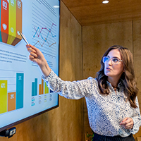 A woman pointing at a bar chart, presenting.