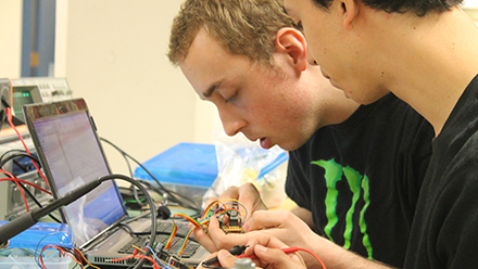 Student connecting wires to a laptop