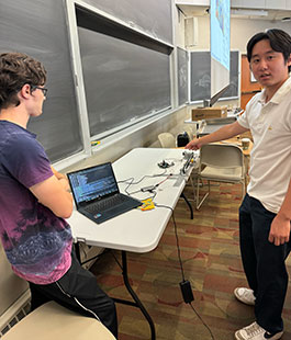 Kamil Banka (L) and Isaac Chen (R) debug their hls4ml implementation on the physical testbed.